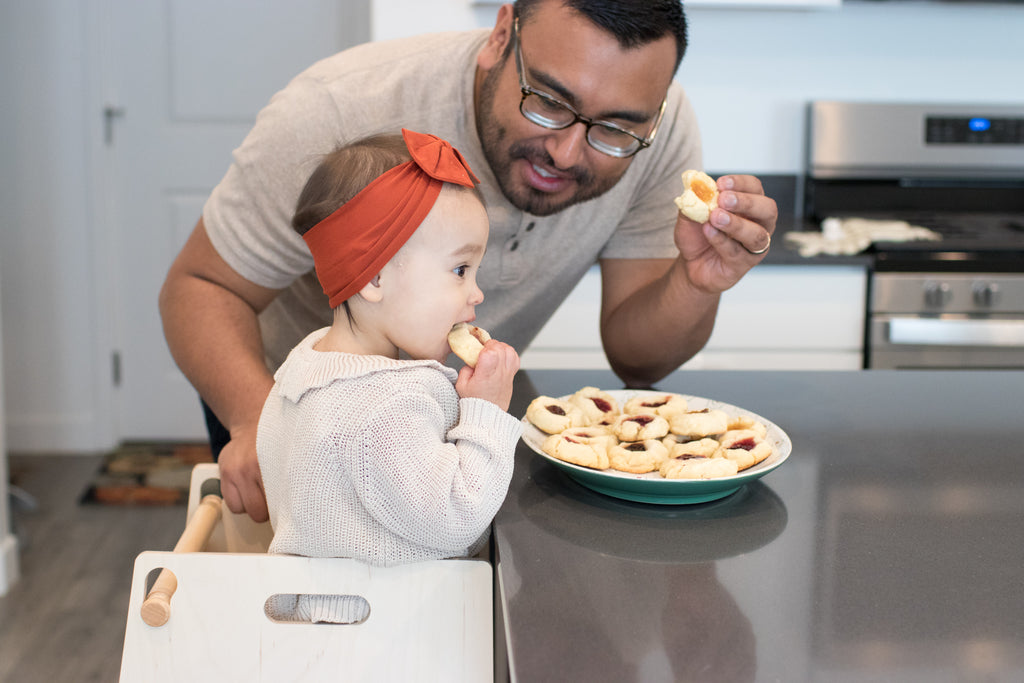 toddler with parent in the kitchen eating cookies