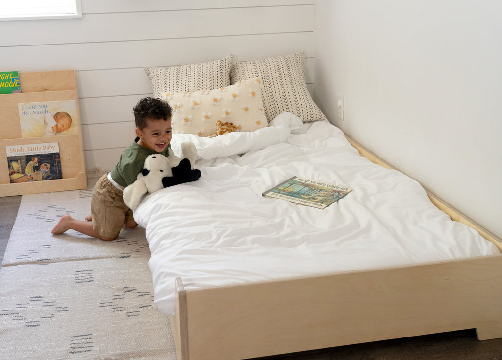young boy playing on the edge of his low floor bed
