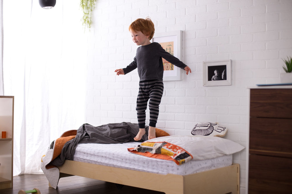 Boy bouncing on a toddler floor bed flipped to the taller configuration