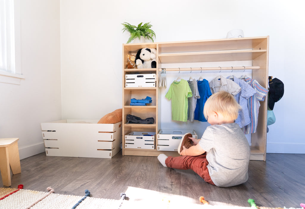 A child getting dressed in front of a Montessori wardrobe