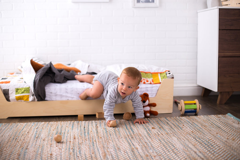 Baby crawling off of a Montessori floor bed independently
