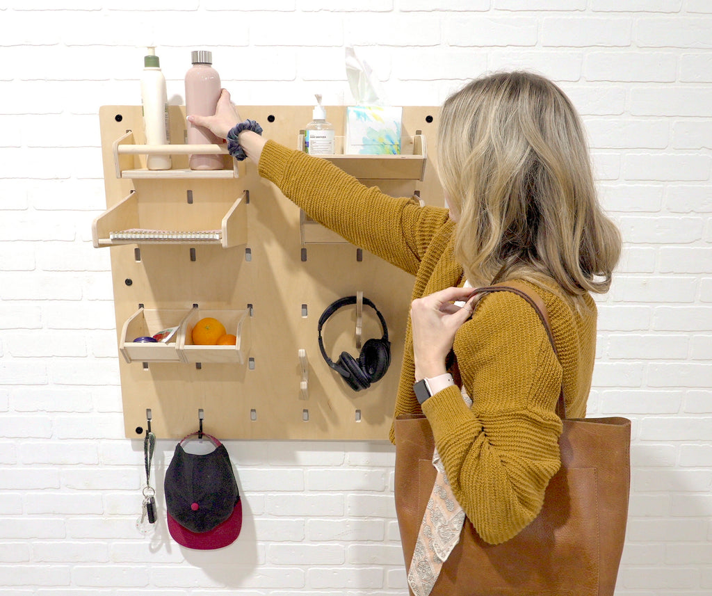 Woman getting bottle out of the entryway MakerWall storage bin.
