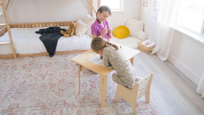 Two kids sitting at a child's table and chair set 