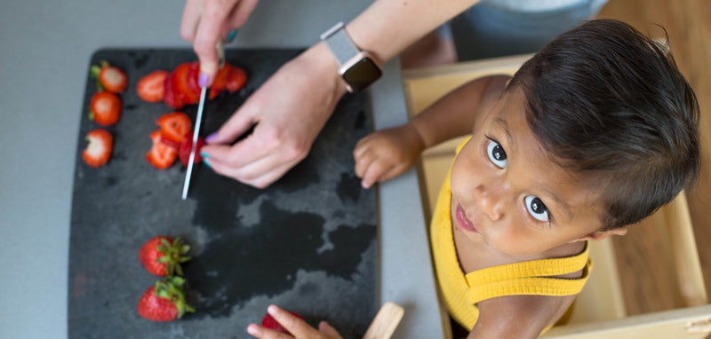 Child cutting strawberries in a Toddler Tower