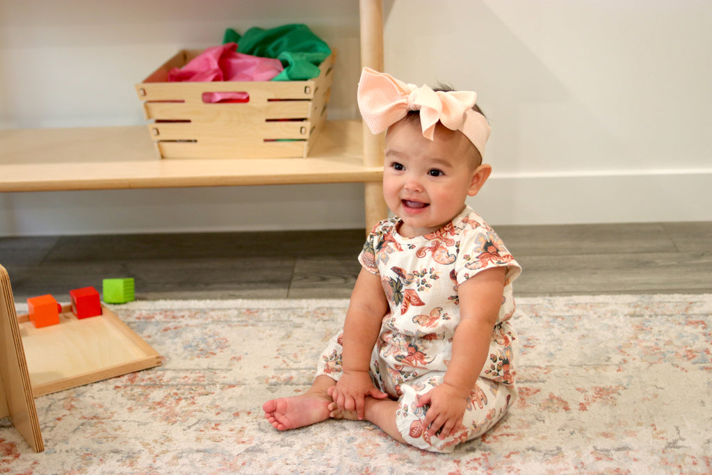 A baby happily sitting in her play room