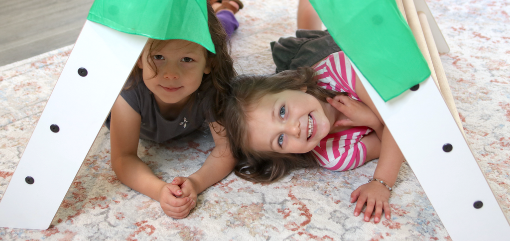 Two children playing underneath a climbing triangle.
