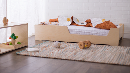 A crib size floor bed with a scooped side