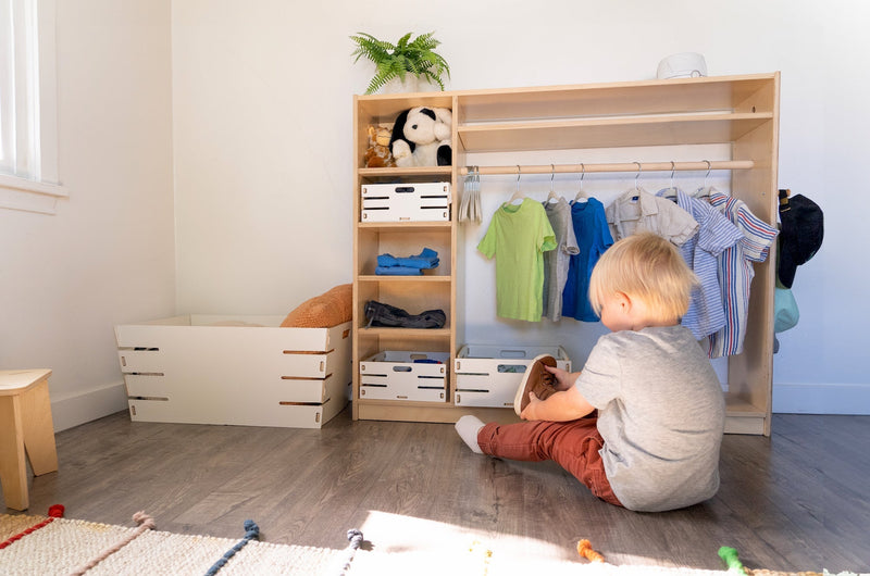 Toddler putting on shoes in front of a Montessori Wardrobe