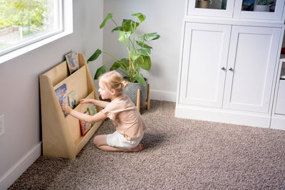 Young girl selecting a book on a forward-facing bookshelf