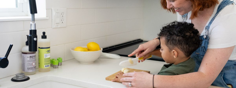 Child and parent cutting a banana 