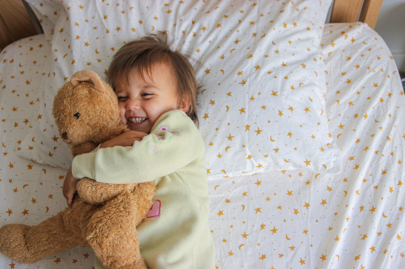 Girl with Teddy Bear lying on bed