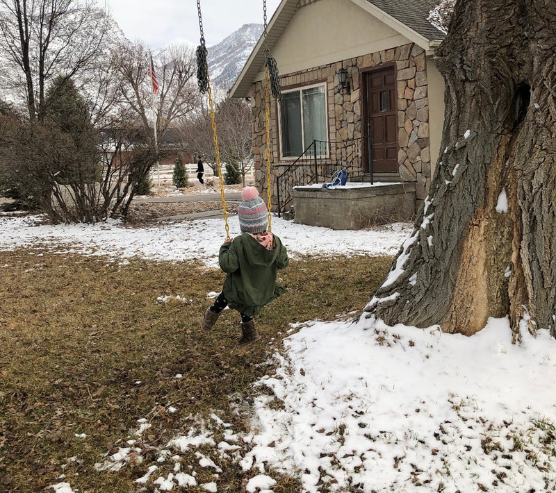 Child swinging outside with snow on the ground