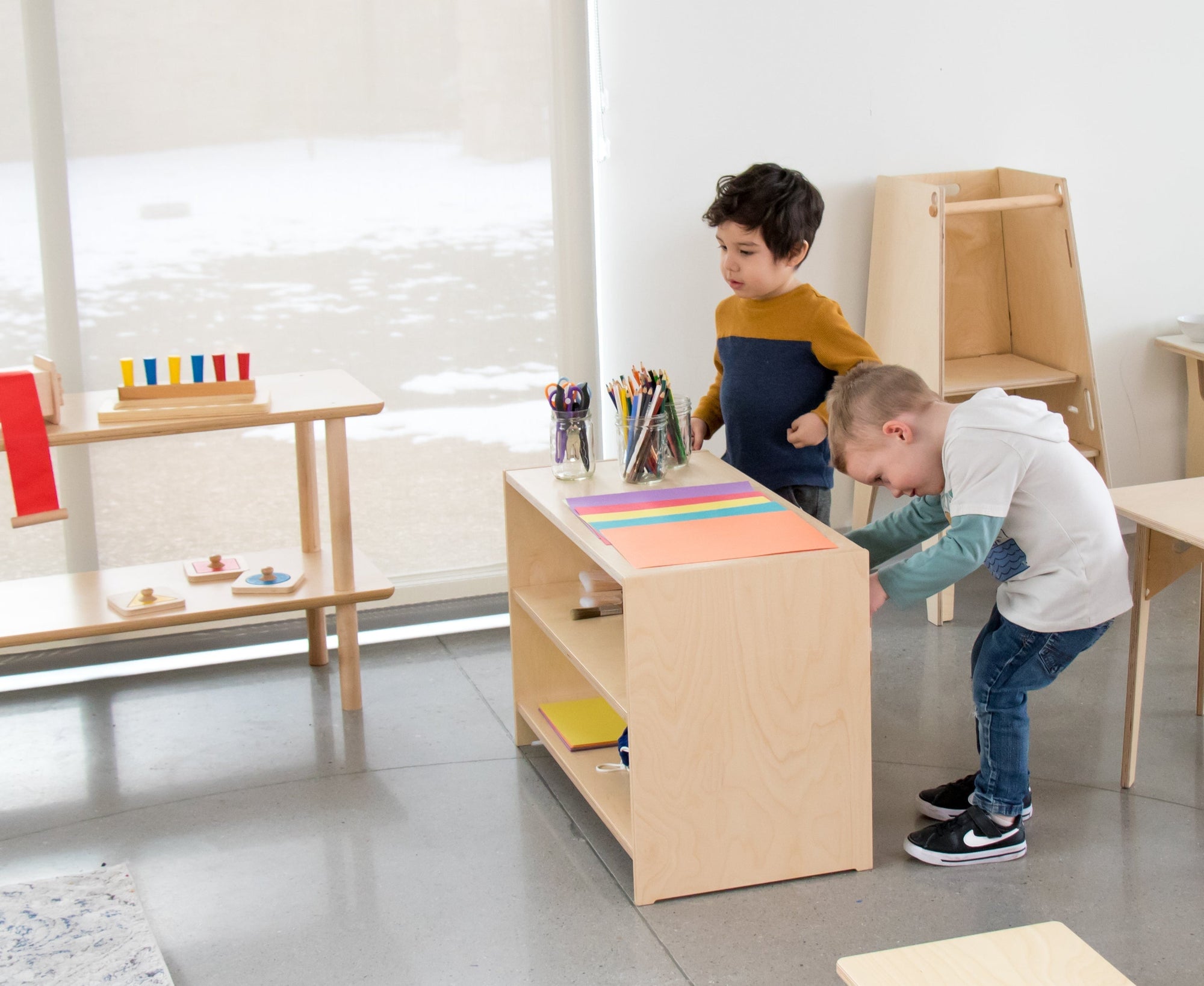 Two Boys crafting on a Montessori Shelf in a classroom