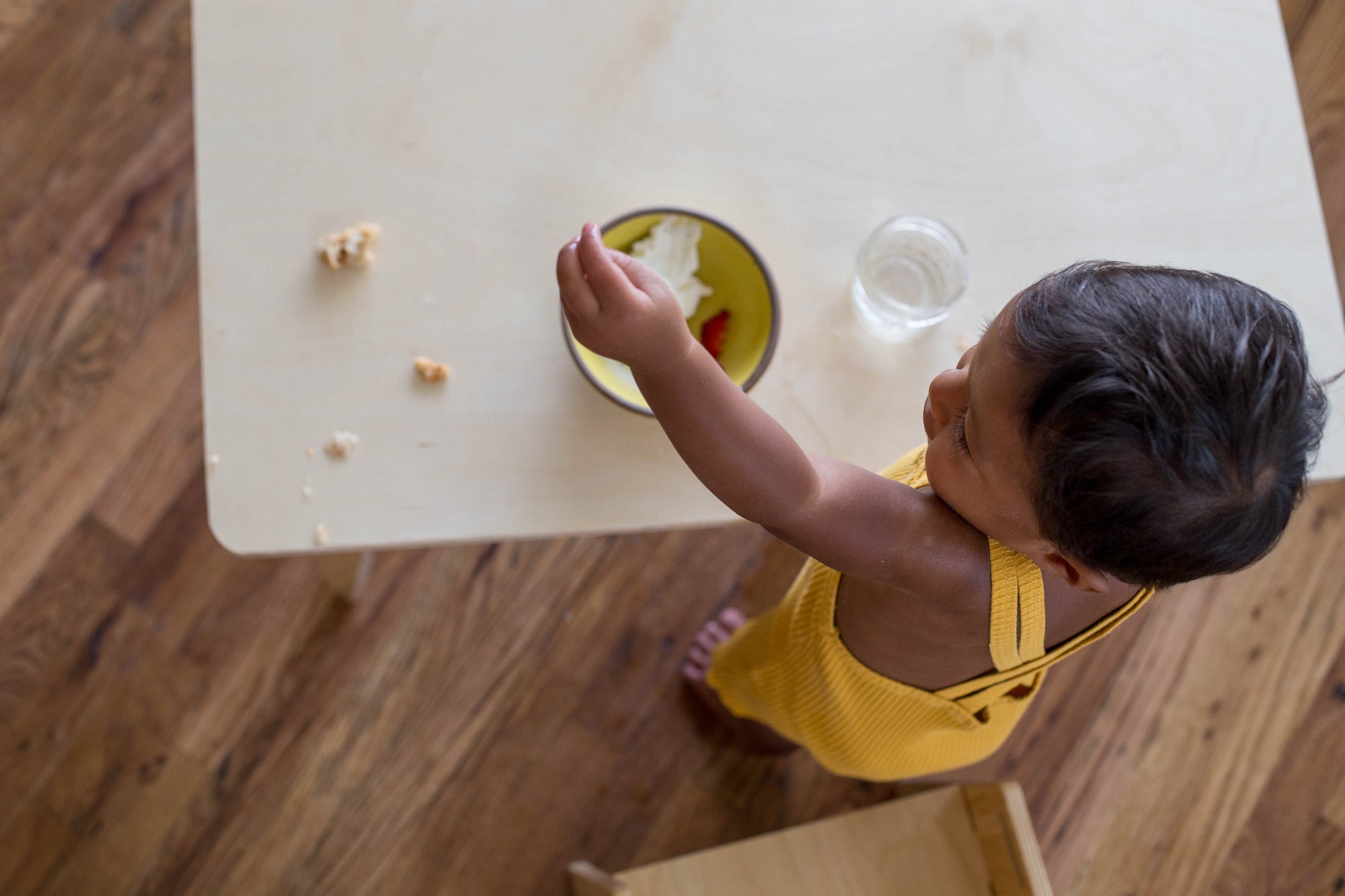 Child sitting at a wooden table eating