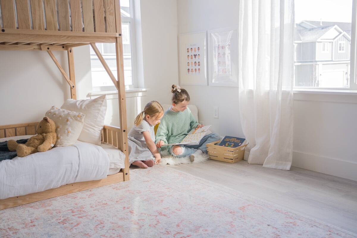 Two girls reading in a corner next to a bunk bed