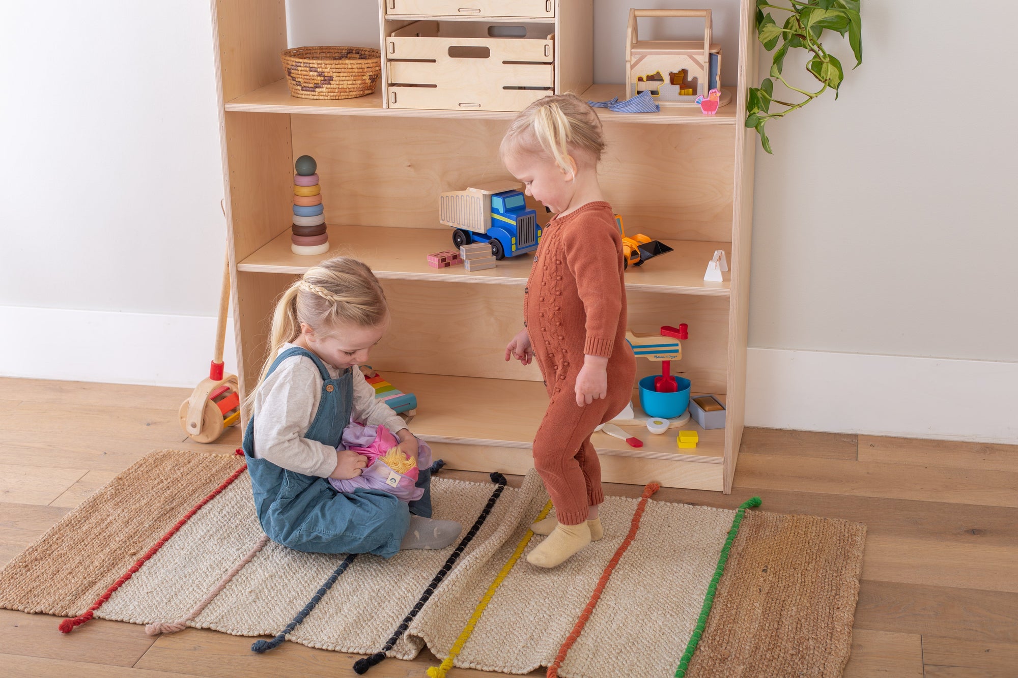 Girls playing in front of a Montessori Toy Rotation Shelf