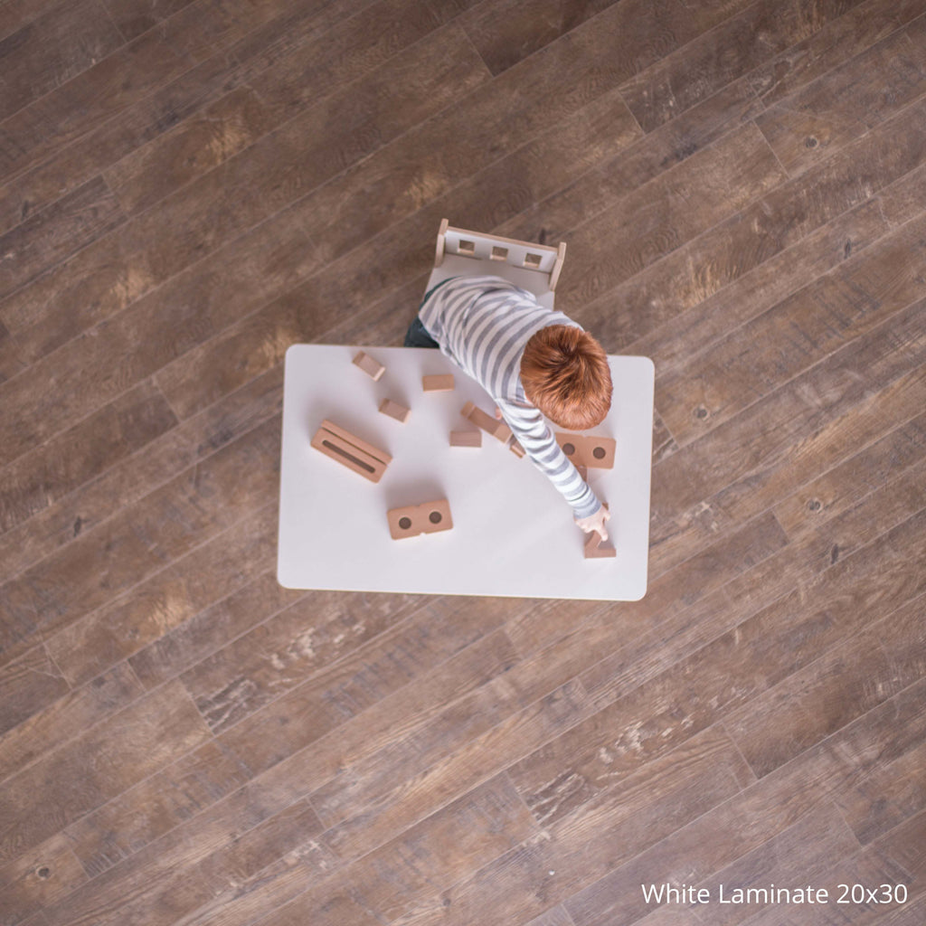 child playing with block on white laminate school table