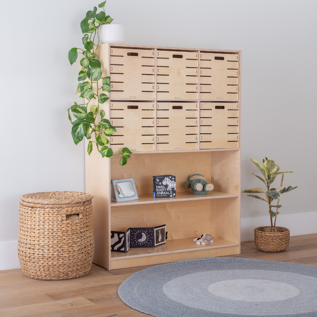 A wooden Montessori shelf showcasing an infant setup with high contrast toys