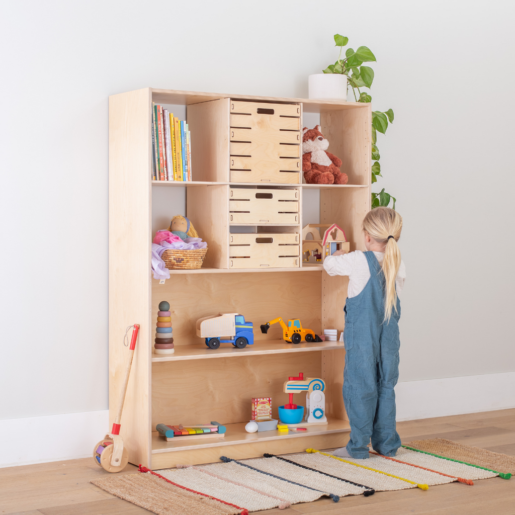 A child selecting a toy from a low Montessori shelf designed for independent play