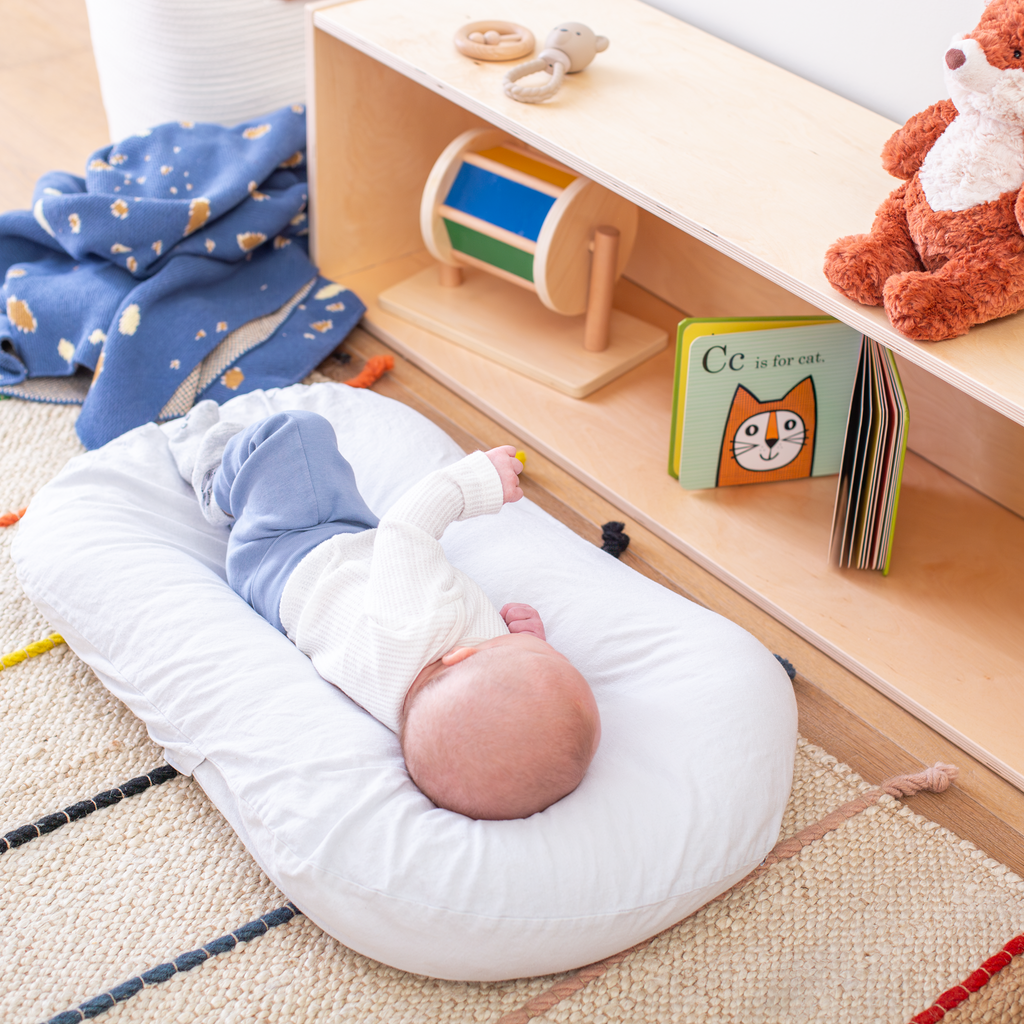 Baby staring at a book on the long backed infant shelf. 