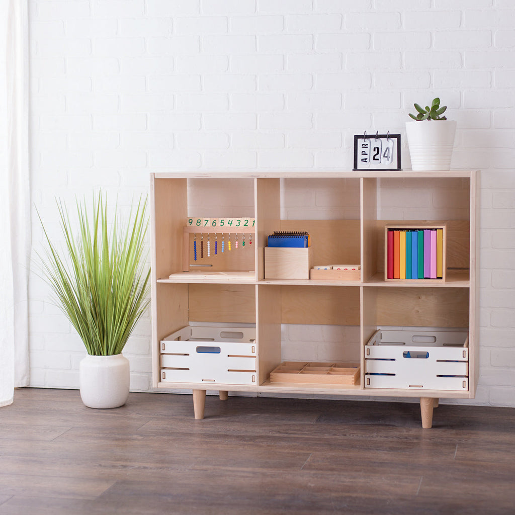 Finished birch wooden eight cube shelf for organizing. In a studio setting with books and Montessori learning resources on the shelves.