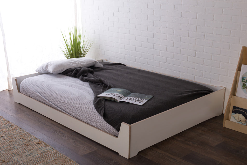 A full size Montessori floor bed in white melamine 