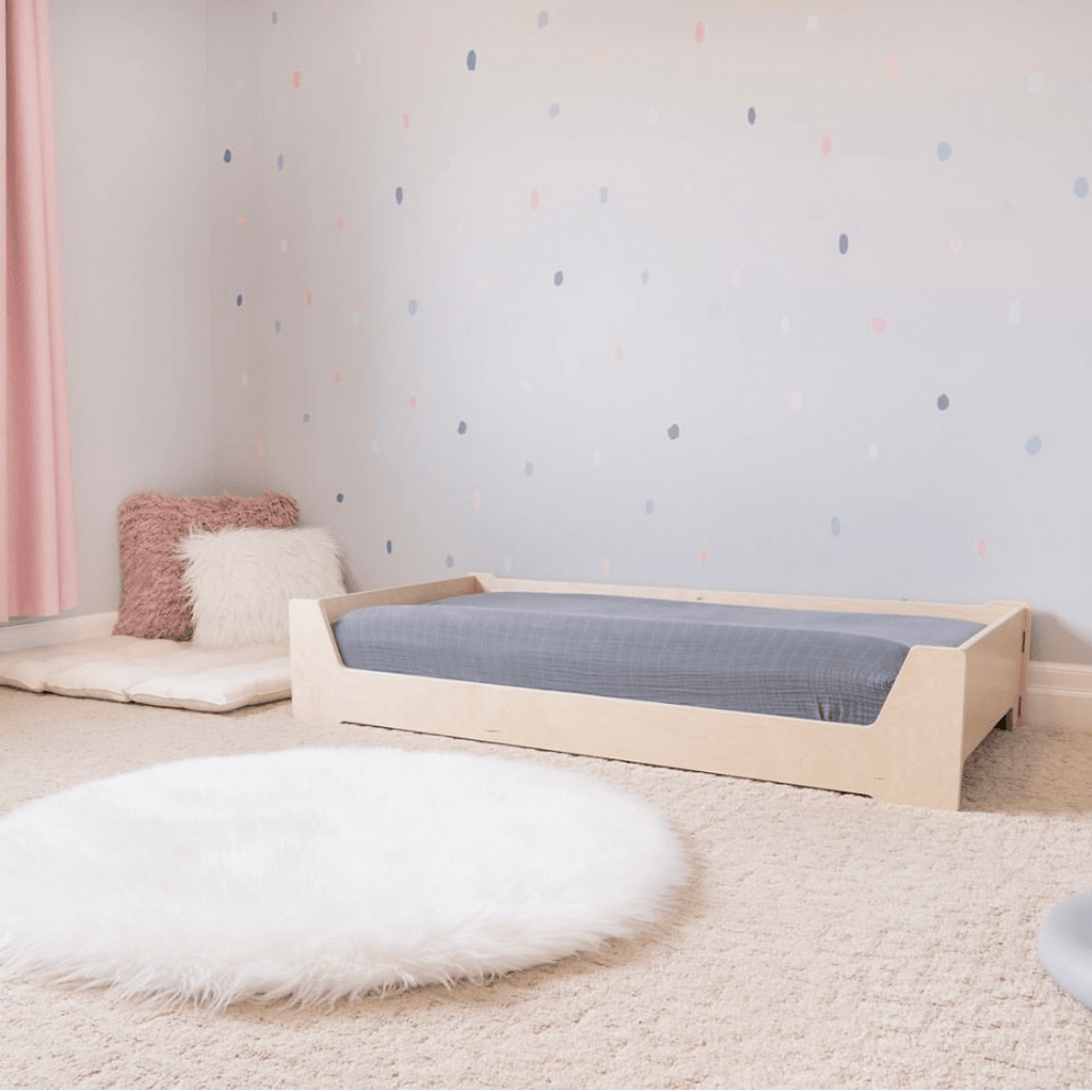 Children's room with a wooden bed, pink curtain, and colorful polka dot wall.