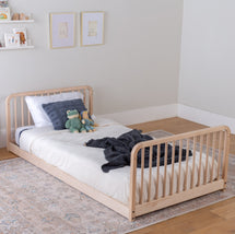 Children's floor bed frame with headboard and footboard in a room setting.