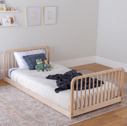Children's floor bed frame with headboard and footboard in a room setting.