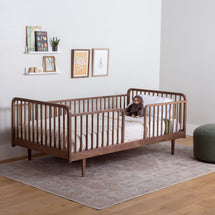 Raised Wooden Floor Bed with High Rails in a room with a rug and wall decorations.