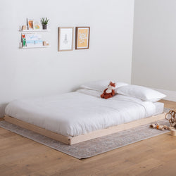 Solid wood platform bed with white bedding in a minimalistic room.