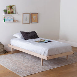 Bedroom with a wooden bed frame, white mattress, and decorative pillows.