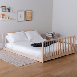 Wooden modular bed with white bedding in a room with light gray walls and wooden flooring.