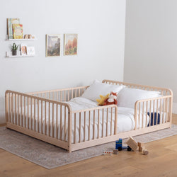 Toddler bed with rails in a bedroom setting with shelves and toys. 