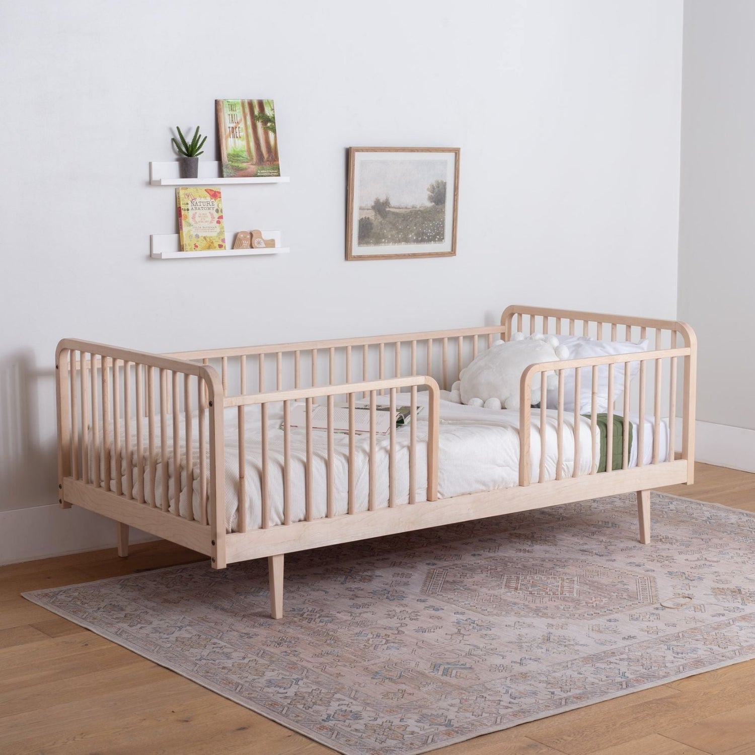 Wooden toddler bed with legs in a room with a rug and wall decorations