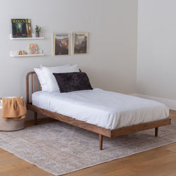 Classic Wooden bed with white bedding in a minimalistic bedroom setting.