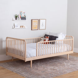 Wooden kids bed with white bedding in a room with a rug and wall decorations.
