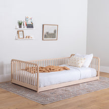 Wooden floor bed with high rails, white bedding, and a blanket in a room with a rug and wall decor.