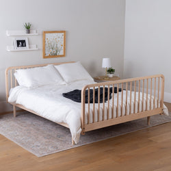 Greenguard certified kids bed with white bedding in a room with a rug and wall decor.