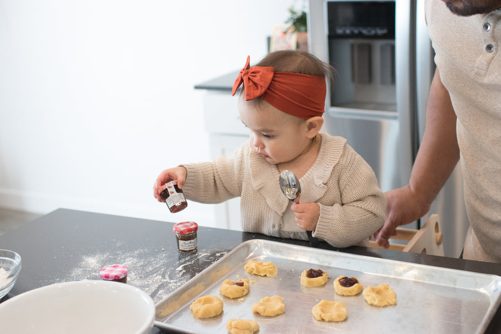 A child in their tower making jam fingerprint cookies