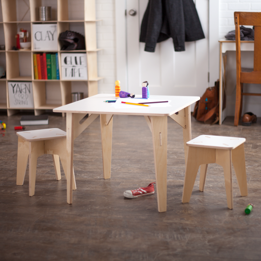 Two School Kids Stools at a rectangular wooden table with a messy background.