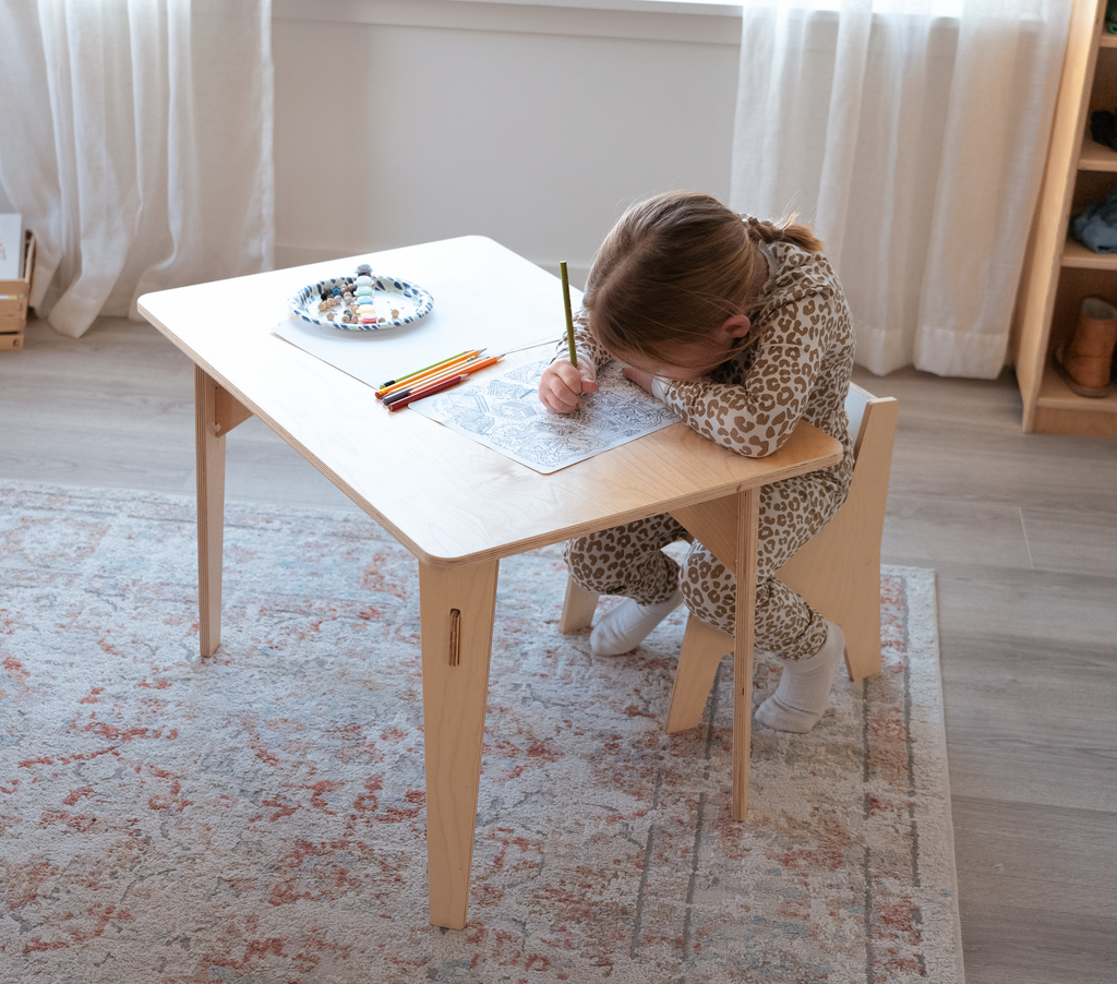 a girl coloring at a kids desk in a bedroom