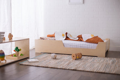 Children's room with a wooden bed, toys, and a white brick wall.