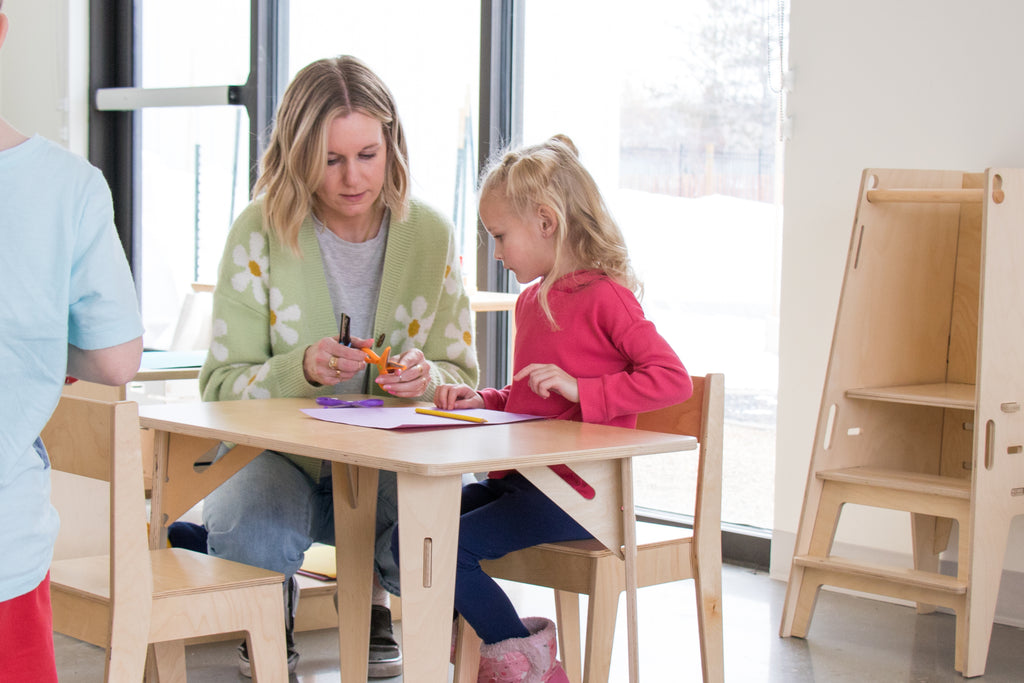 A teacher and child use a Montessori table and chair