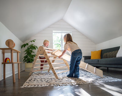 two children using a pikler triangle with a ramp