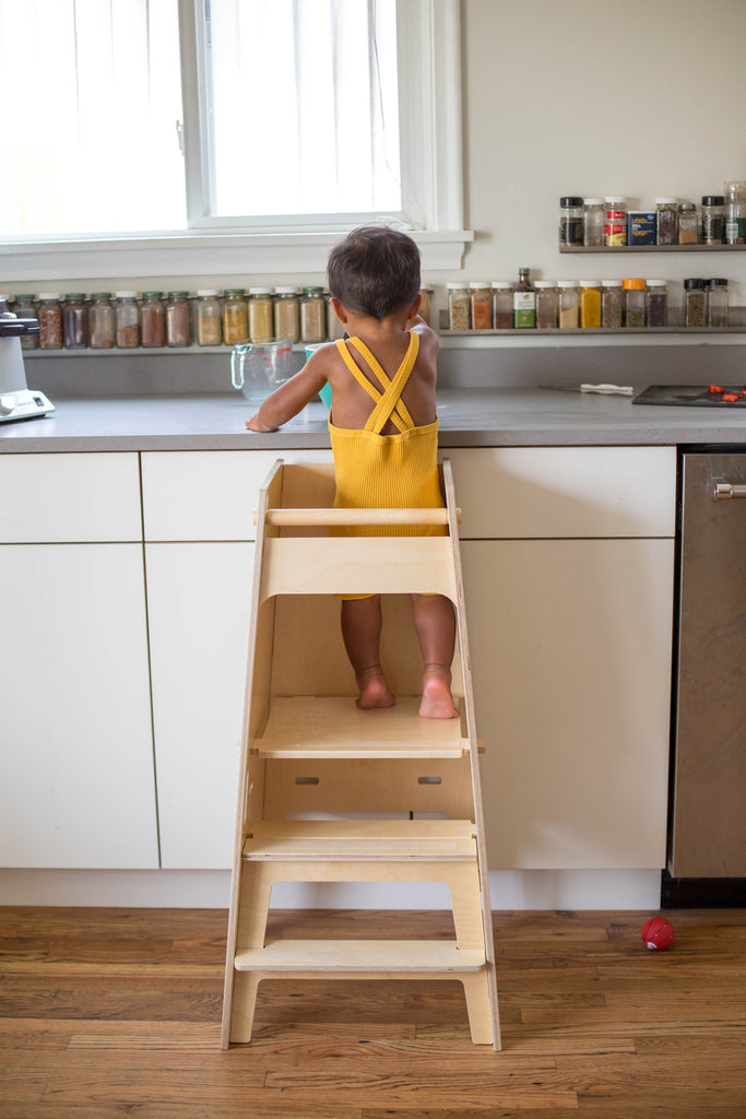 Small boy at the kitchen counter in a Montessori kitchen helper (from behind)