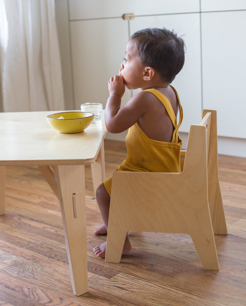 Little boy eating at a small toddler table with feet flat on the floor