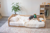 The Sosta oak floor bed with two headboards and a full side rail with a little boy laying on the bed
