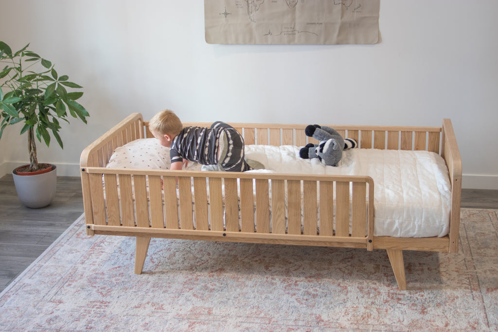 A little boy climbs on the floor bed frame with two headboards, a full side board, a 3/4 side board, and legs 