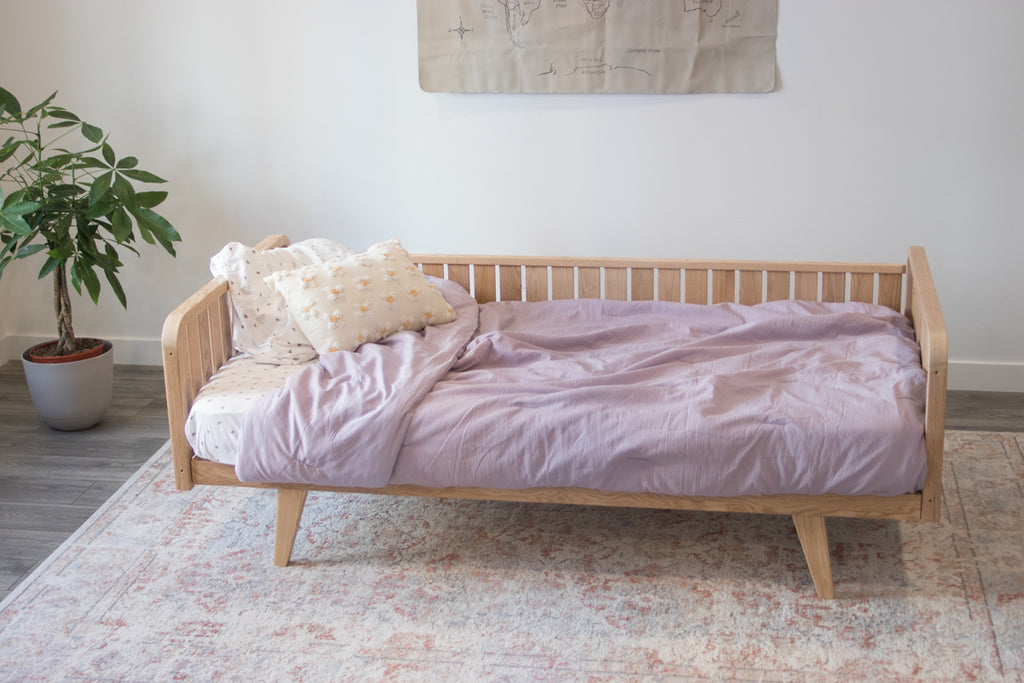 An oak wood bed frame with two headboards, a full side rail, and legs 